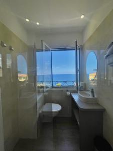 a bathroom with a toilet and a sink and a window at Hotel Restaurant Christophe Colomb in Calvi