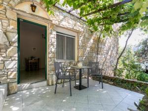 a patio with a table and chairs next to a stone building at Petra Mare Apartments in Alyki