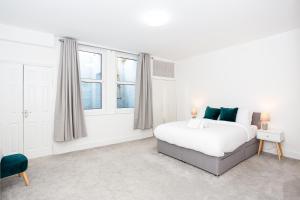 a white bedroom with a bed and two windows at Beach Walk by Sorted Stay in Southend-on-Sea