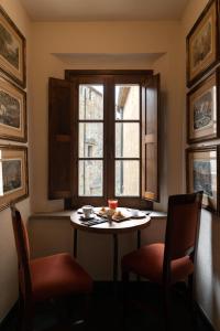 - une table et des chaises dans une chambre avec fenêtre dans l'établissement Hotel Della Fortezza, à Sorano