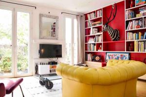 ein gelbes Sofa im Wohnzimmer mit einem TV in der Unterkunft Jolie maison de ville à 5 minutes de Paris pour 5 voyageurs parking inclus in Clichy