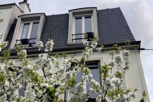 einem blühenden Baum vor einem Haus mit Fenstern in der Unterkunft Jolie maison de ville à 5 minutes de Paris pour 5 voyageurs parking inclus in Clichy