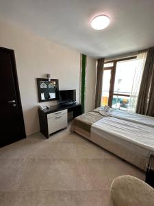 een slaapkamer met een bed, een bureau en een raam bij Briz Beach apartments - section B in Sunny Beach