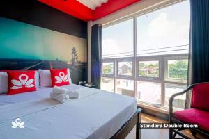 Habitación con cama con almohadas rojas y ventana. en Sabel Travelers Inn en Laoag