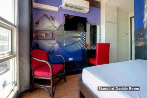 um quarto com uma cama e duas cadeiras e uma televisão em Sabel Travelers Inn em Laoag