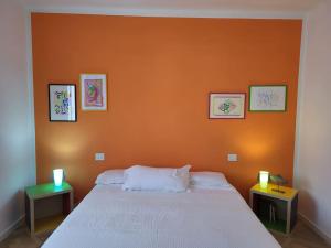 1 dormitorio con pared de color naranja y 1 cama con 2 mesas en Casa del Golfo 2, en Riccò del Golfo di Spezia