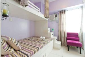 a small bedroom with a bed and a pink chair at Condo Studio Luxe in Princeton Residences in Manila