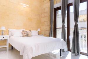 ein Schlafzimmer mit einem weißen Bett und einem großen Fenster in der Unterkunft Casa Deguara townhouse Rabat Malta in Rabat