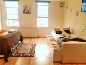 1 dormitorio con 2 camas y 2 ventanas en Comfortable Studio flat near Central London, en Londres