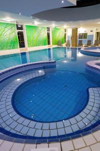 una piscina en un edificio con azulejos azules en Napfeny Hotel, en Zalakaros