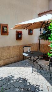 uma mesa e cadeiras sob um guarda-sol num pátio em GreenHouse_Anzio em Anzio