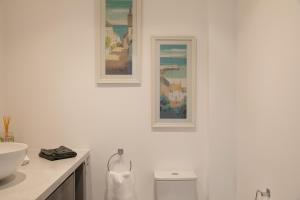 a white bathroom with two pictures on the wall at Rutland Heights in Torquay