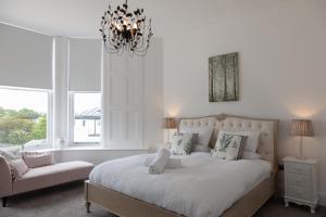 a white bedroom with a large bed and a chandelier at Rutland Heights in Torquay