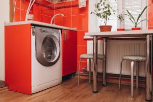 a washing machine in a kitchen with a counter and stools at Квартира в центре города in Sumy