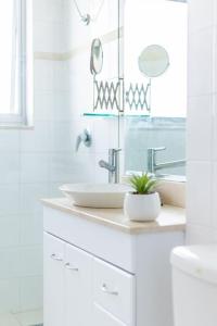 a white bathroom with a sink and a mirror at Mosman Views, 2bed, Parking, 15min Walk to Beach in Sydney