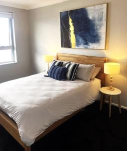 1 dormitorio con 1 cama grande y 2 lámparas. en Mosman Views, 2bed, Parking, 15min Walk to Beach en Sídney