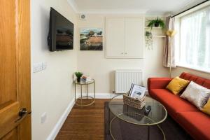 un soggiorno con divano rosso e tavolo in vetro di Where Style & Convenience Combine- Photo ID Required a Londra