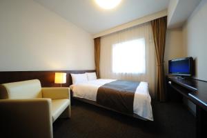 pokój hotelowy z łóżkiem i telewizorem w obiekcie Dormy Inn Sendai Station Natural Hot Springs w mieście Sendai