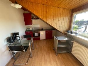 una pequeña cocina con armarios rojos y una ventana en Apartment Nürnberg, en Núremberg