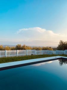 a white fence and a swimming pool next to a fence at Olea b&b in Montecosaro