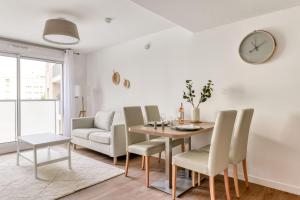 une salle à manger avec une table, des chaises et une horloge dans l'établissement OVELIA Montpellier - Les Balcons de Montcalm, à Montpellier