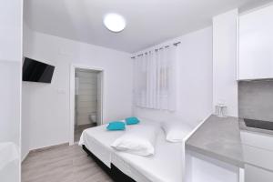 a white bedroom with a bed with blue pillows at Silver stars 1 in Zadar
