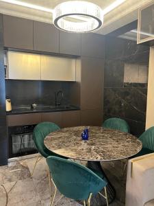 a kitchen with a table and green chairs at Apart Elena Arcadia Sea View in Odesa