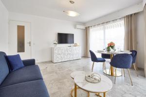 Cannes centre-Palais-200m des plages في كان: غرفة معيشة مع أريكة زرقاء وطاولة
