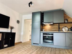 eine große Küche mit Küchengeräten aus Edelstahl und Holzböden in der Unterkunft Moderne Ferienwohnung Zweifall in Stolberg