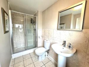 y baño con aseo, ducha y lavamanos. en Large House with Free Parking and Long Stay Offers, en Leicester