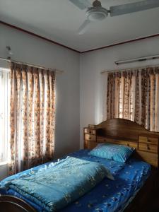 1 dormitorio con 1 cama con cabecero de madera y cortinas en juneli raat homestay pokhara en Pokhara