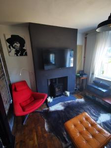 uma sala de estar com uma cadeira vermelha e uma lareira em Newly Renovated 3 bedroom house em Taibach