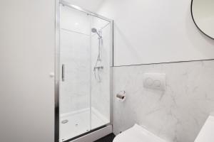 uma casa de banho branca com um chuveiro e um WC. em Villa Oliver Budapest em Budapeste