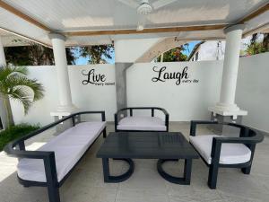 two beds and a table on a patio at Linda's Little Lincoln in Watamu