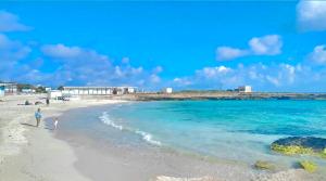 a woman and a child walking on a beach at Stabilimento Lido Burrone in Favignana