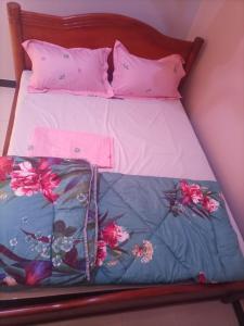a bed with pink and blue sheets and pink pillows at Pearl furnished residence in Buloba