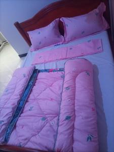 a bed with a pink comforter and butterfly pillows at Pearl furnished residence in Buloba
