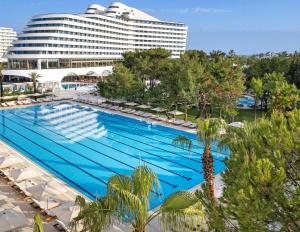 a large swimming pool with a hotel in the background at Titanic Deluxe Lara in Lara