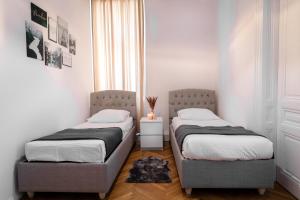 2 Betten in einem kleinen Schlafzimmer mit Fenster in der Unterkunft Infinity Homes - Stylish 3-Bedroom Haven in the Heart of Vienna! in Wien