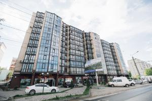 un gran edificio con coches estacionados frente a él en Atlant luxury VIOLET Apart on Golovna стильні апартаменти поряд з ТЦ ДЕПОТ БЕЗКОНТАКТНЕ ЗАСЕЛЕННЯ en Chernivtsi