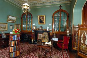 uma sala de estar com lareira e um lustre em Larnach Lodge & Stable Stay em Dunedin