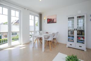 - une salle à manger blanche avec une table et des chaises blanches dans l'établissement Achtern Diek Wohnung 14, à Boltenhagen