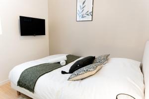 een slaapkamer met een wit bed met kussens en een televisie bij Le Tropical - Beau logement centre - Gare - Tram in Le Mans