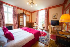 a bedroom with a bed and a desk and a television at Château Hôtel Du Colombier in Saint Malo