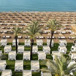 an overhead view of a beach with white lounge chairs and palm trees at Titanic Deluxe Lara in Lara