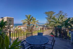 a blue table and chairs on a deck with the ocean at Ballito Bay Holiday Apartment in Ballito