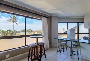 a room with a large window and two bar stools at Ballito Bay Holiday Apartment in Ballito