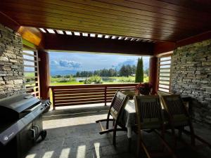un patio con mesa, sillas y una ventana grande en Pirin Golf Lake House, en Bansko