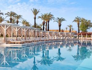 a pool at the resort with chairs and palm trees at Titanic Deluxe Lara in Lara