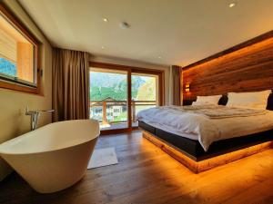 a bedroom with a tub and a bed and a window at Luxury Chalet Engedi in Saas-Fee